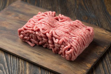 Ahşap arka plan üzerinde kesme tahtası üzerinde kıyılmış et,