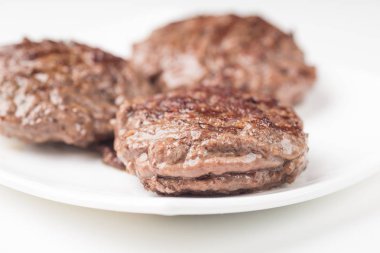 Gıda: üç taze çiğ ev yapımı pirzola beyaz arka plan üzerinde izole bir plaka üzerinde