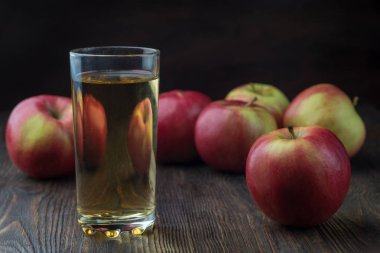 Taze organik tarım elma suyu içinde gözlük ile eski rustik ahşap masa, kopya alanı üzerinde ham bütün ve kırmızı elma