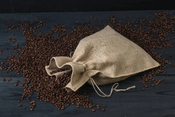 Coffee beans in bags. Fresh coffee beans sack on dark rustic wooden background.