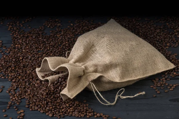 Coffee beans in bags. Fresh coffee beans sack on dark rustic wooden background.