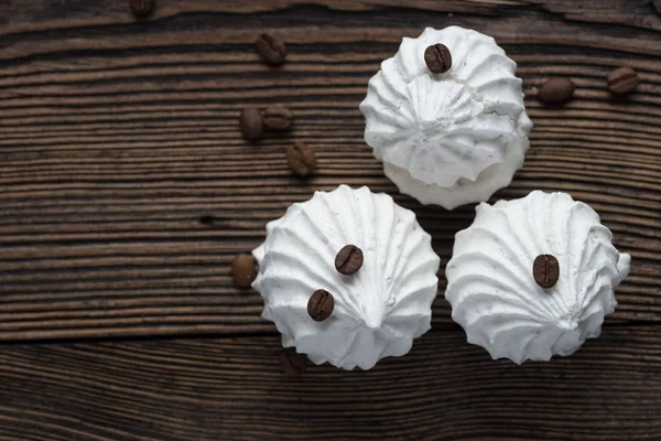 Homemade marshmallow cakes made from natural ingredients on a wooden surface with crumbled coffee beans
