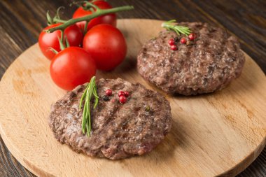 Izgara burger pirzola sığır eti kıyma biberiye ve ahşap arka plan üzerinde kiraz domates ile.