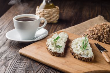 Rustik ahşap arka plan kopya alanı ile kahve fincan ile kahvaltıda ekmek ve tereyağı. Sabah kahvaltı kahve, krem peynir ve tost ile.