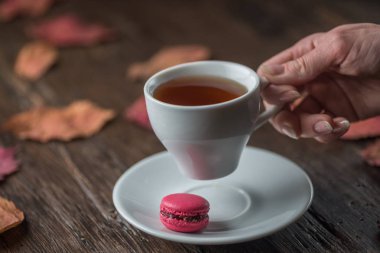 Fincan çay yaprakları ve ekose üstten görünüm sonbahar ahşap arka plan üzerinde tutan kadının elinde limonlu. Sıcak içecek konsepti.