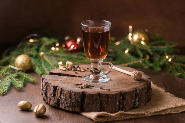 Glass cup with hot tea. Cozy time together. China Tea time on the Christmas Eve . New Years lights on the background. Lighted candles, hot drink and cinnamon sticks.