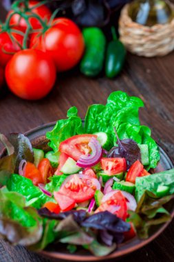 Karışık yeşil taze yeşil salata yaprakları, domates, soğan ve koyu ahşap masa üzerinde salatalık. Yeme temiz ve Diyet yemekleri.