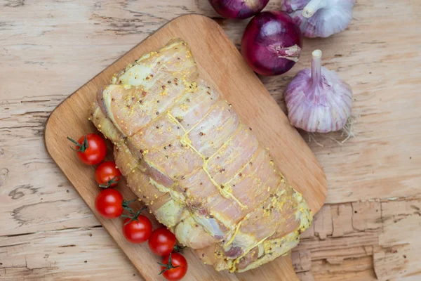 Raw cut of pork shoulder on board with vegetables. Fresh pork meat on wooden cutting board.