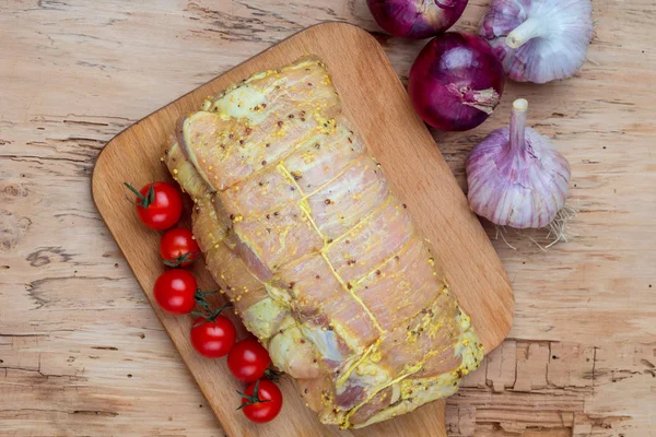 Raw cut of pork shoulder on board with vegetables. Fresh pork meat on wooden cutting board.