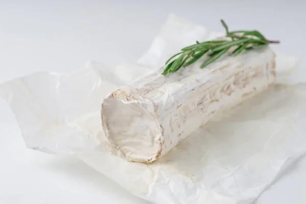 Slices goat cheese and goat cheese piece with rosemary on white background. Culinary cheese eating.