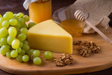 Ahşap üzerine üzüm, zeytin, bal ile peynir