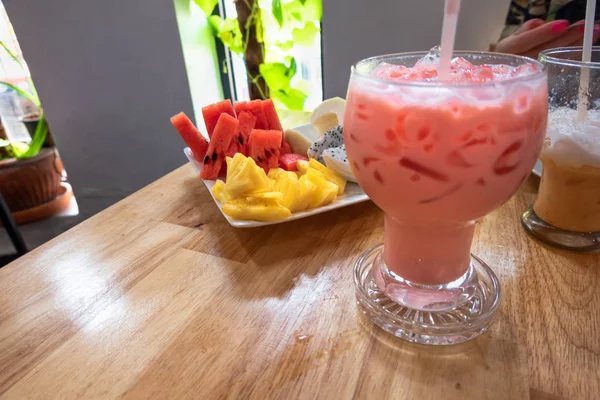 Té de hielo rosa tailandés en la mesa con plato de frutas —  Fotos de Stock