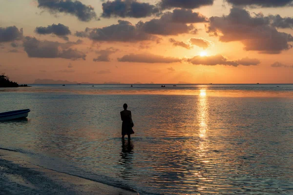 Mujer entra en el mar, playa bajo la hora del atardecer — Foto de Stock