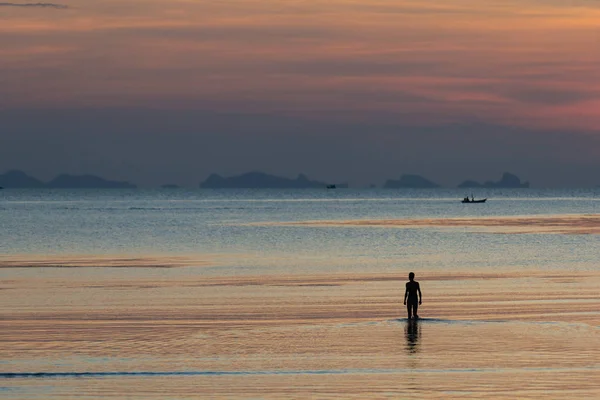 Pescador de pie en una marea baja en el fondo del cielo de la noche en th — Foto de Stock