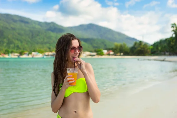 Ung kvinna med apelsinjuice på stranden i Thailand — Stockfoto