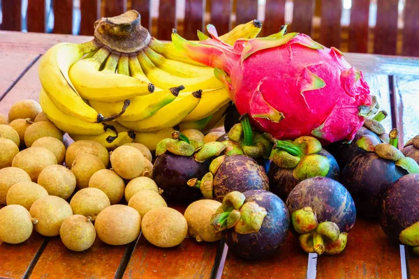 Frutas tropicales exóticas sobre fondo de madera, comida saludable, vegeta — Foto de Stock