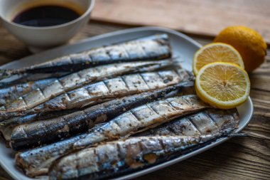 Limon ve balık şeklinde beyaz bir tabak üzerinde Füme saury 