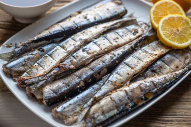 Limon ve balık şeklinde beyaz bir tabak üzerinde Füme saury 