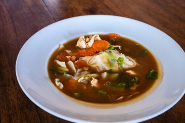 Beyaz tabakta istiridye çorbası karışık tofu ve tavuk.