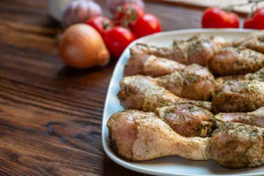 Beyaz çanak otlar ve baharatlar ile Çiğ tavuk bacakları.