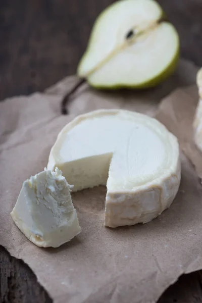 Bit illaluktande camembert ost på ett rustikt träbord — Stockfoto