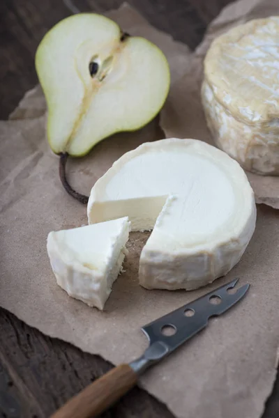 Bit illaluktande camembert ost på ett rustikt träbord — Stockfoto