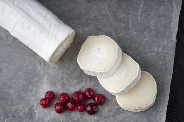 Queso de cabra fresco con rodajas de bayas rojas sobre papel . — Foto de Stock