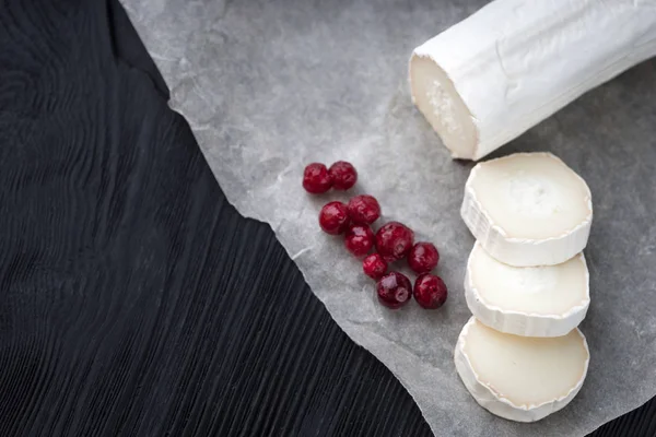 Queso de cabra fresco con rodajas de bayas rojas sobre papel . — Foto de Stock