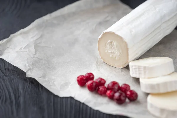 Queso de cabra fresco con rodajas de bayas rojas sobre papel . — Foto de Stock