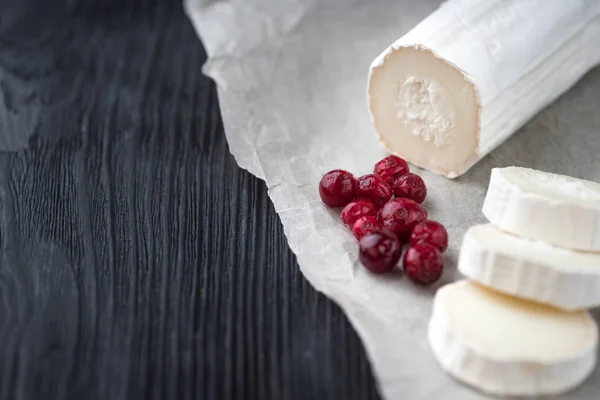 Queso de cabra fresco con rodajas de bayas rojas sobre papel . — Foto de Stock