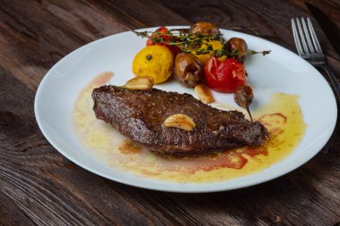 Beyaz bir tabakta dinlenen pişmiş sebzeli kaburga-göz biftek