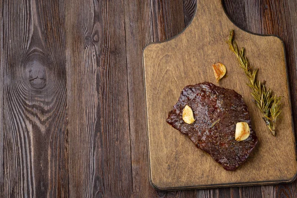 Rindersteak mit Rosmarinzweigen auf einem Holztisch. — Stockfoto