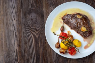 Beyaz bir tabakta dinlenen pişmiş sebzeli kaburga-göz biftek