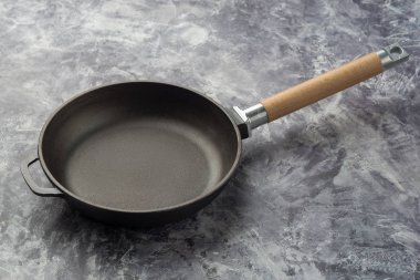 Koyu gri arka plan üzerinde boş dökme demir kızartma tavası.