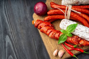 Fesleğen ve baharatlar ile ahşap bir tahta üzerinde kurutulmuş sosis. Rustik fo