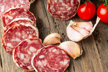 Ahşap arka planda soğuk biber ile dilimlenmiş füme salam.