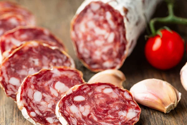 Salami fumé tranché au poivre frais sur fond de bois . — Photo