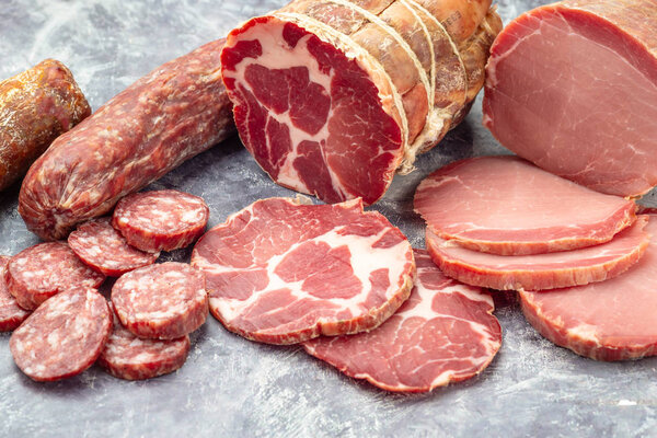Assortment of delicious deli meats on wooden board