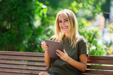 Bankta tablet ile genç mutlu gülümseyen kadın