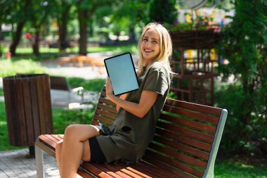 Genç mutlu kadın boş bir tablet ekranı gösteriyor