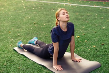 İnce, güzel kadınlar yoga pozisyonlarını paspasın üzerinde çalışırlar.