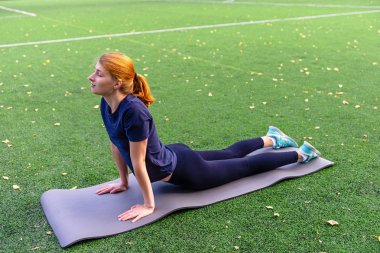 İnce, güzel kadınlar yoga pozisyonlarını paspasın üzerinde çalışırlar.