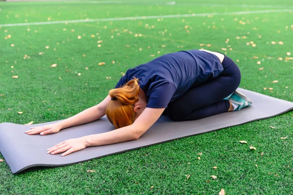 Slim beautiful women practices yoga poses on the mat  at the out — Stock Photo, Image