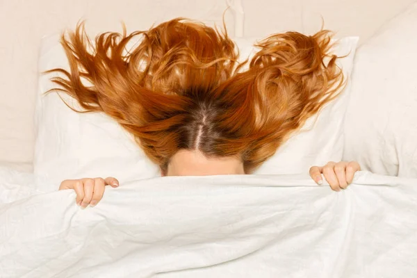Chica escondida debajo de las cubiertas en la cama, foto de vista superior. Joven hermosa — Foto de Stock