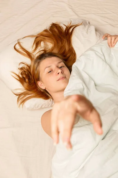Portré egy fiatal nőről, aki az ágyban fekszik a takaró alatt. — Stock Fotó