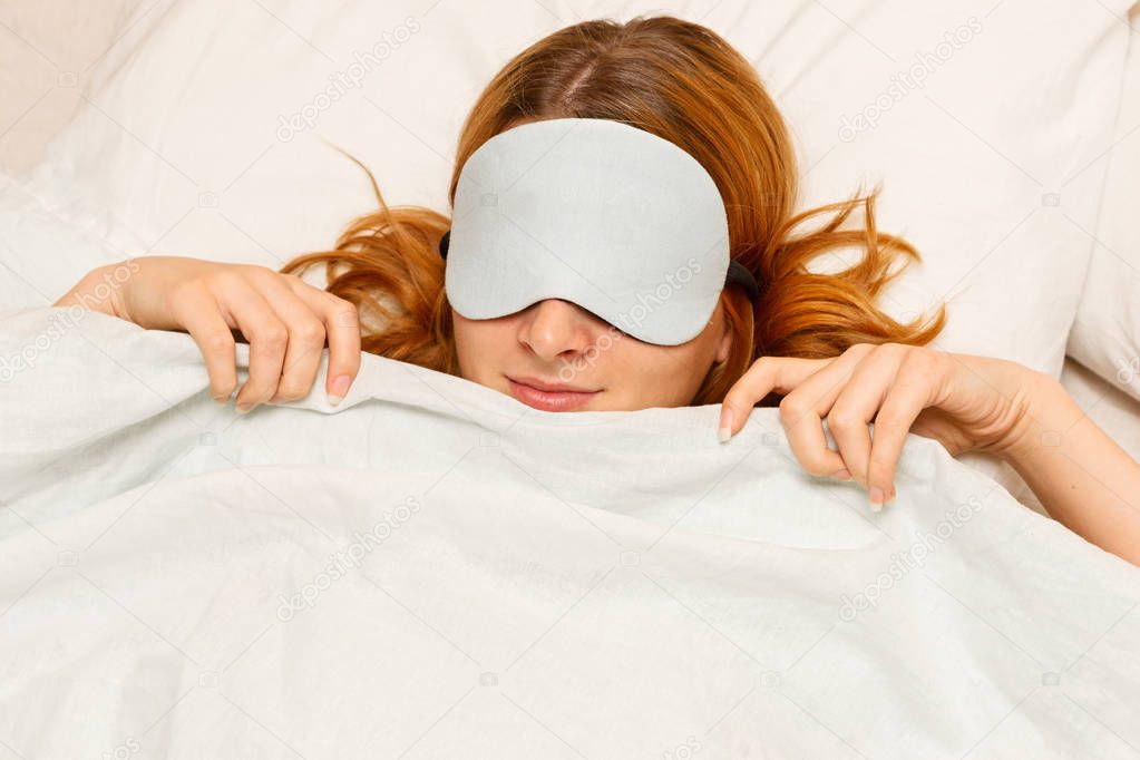 A young woman sleeping with a eye covering mask.