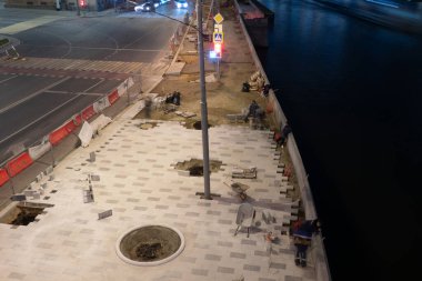 İnşaat işçileri inşaat alanında gece yol için beton kaldırımlar kuruyor ve düzenliyorlar..