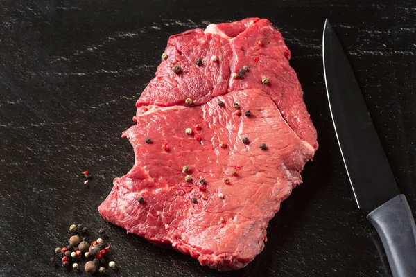 新鲜的生牛肉肉 黑板背景下的鲜红色肉片 配刀和香料 — 图库照片