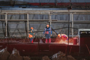 Profesyonel işçi metali elektrikli testereyle keser. Kıvılcımlar pınarı. İnşaat alanında yangın güvenliği. Tehlike ve sıkı çalışma.