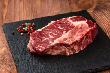 Taş tahtada taze çiğ ana Angus bifteği Striploin, Rib Eye. Karanlık bir ahşap arka planda